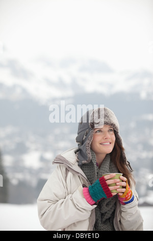 Smiling woman drinking coffee in snow Banque D'Images