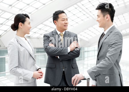 Professionnels des associés ayant la conversation dans le hall de l'aéroport Banque D'Images