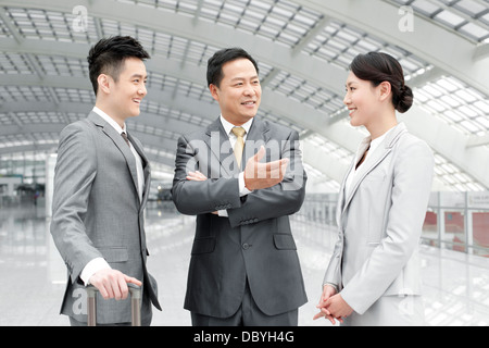 Professionnels des associés ayant la conversation dans le hall de l'aéroport Banque D'Images