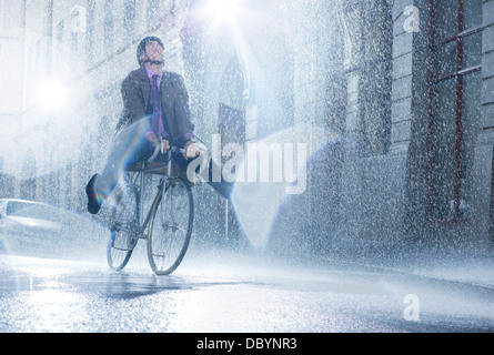 Businessman riding bicycle in rainy street Banque D'Images