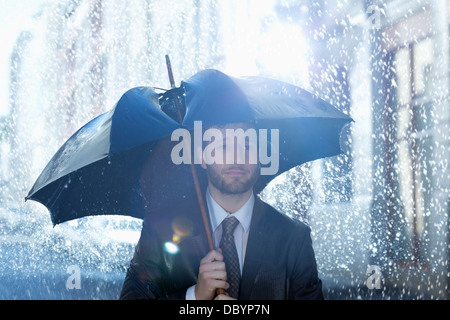 Frustrés businessman with broken umbrella in rain Banque D'Images