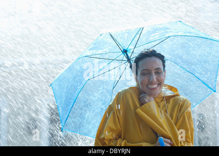 Happy woman under umbrella in rain Banque D'Images