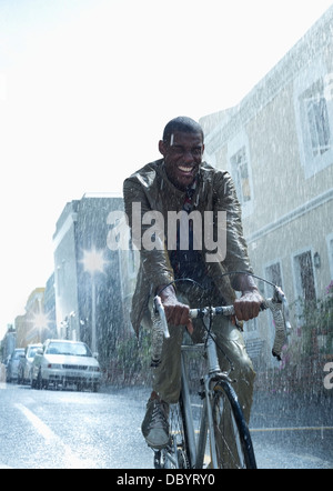 Happy businessman riding bicycle in rain Banque D'Images