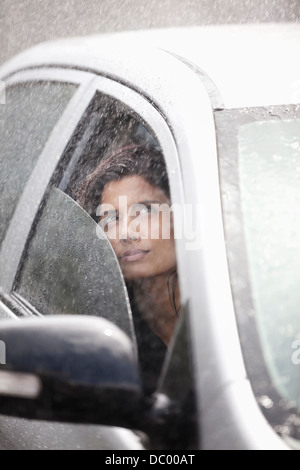 Businesswoman in car looking up at rain Banque D'Images