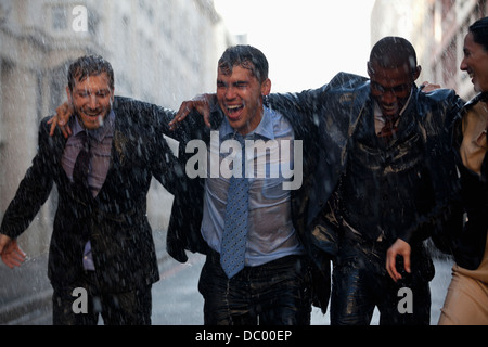 Heureux hommes d'walking in rainy street Banque D'Images