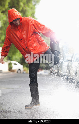 Homme debout sur une jambe à Rainy Street Banque D'Images