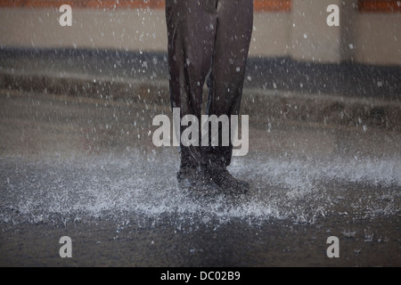 Businessman standing in rainy street Banque D'Images