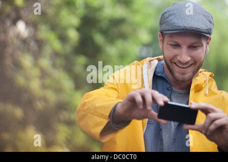 Happy man taking photograph with camera phone Banque D'Images