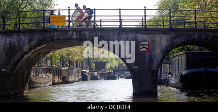 Amsterdam Pays-Bas Hollande Europe bridge avec des vélos sur canal avec des bateaux de croisière péniche péniche longeant le Canal Banque D'Images