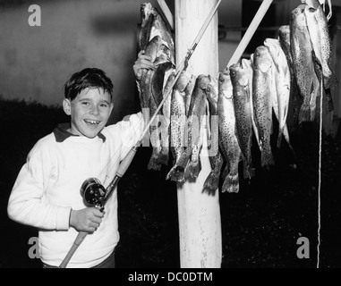 1950 SMILING BOY arborant fièrement SA PRISE DE POISSON LOOKING AT CAMERA Banque D'Images