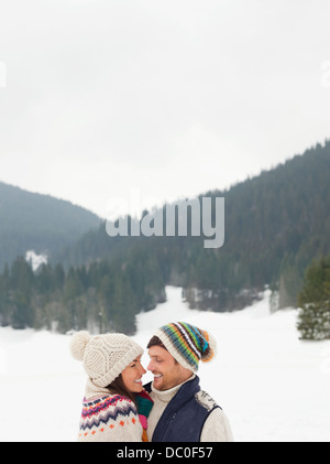 Heureux couple face to face in snowy field Banque D'Images