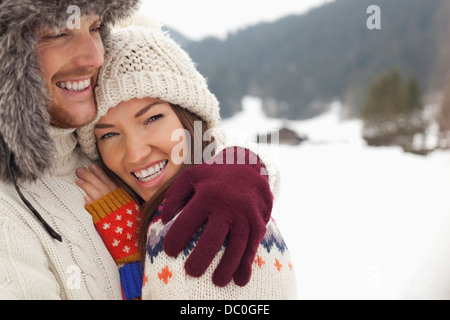 Close up portrait of happy couple hugging in snowy field Banque D'Images