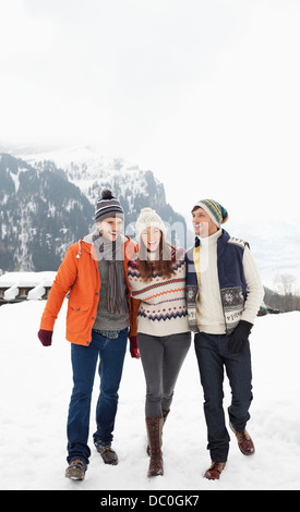 Happy friends walking in snowy field Banque D'Images