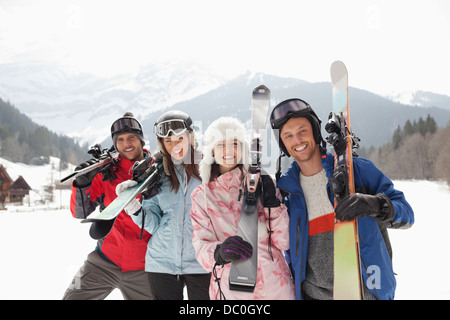 Portrait of smiling friends with skis in snowy field Banque D'Images