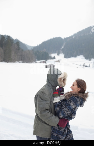 Heureux couple hugging in snowy field Banque D'Images