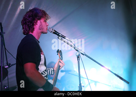 Gros plan sur un homme séduisant chantant et jouant de la guitare devant des feux bleus à un concert de rock and roll Banque D'Images