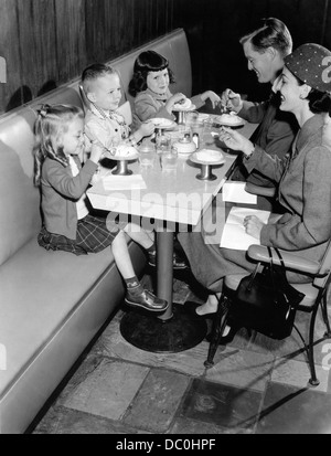 1950 FAMILY EATING ICE CREAM À UN DINER Banque D'Images