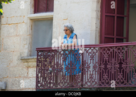 Une vieille dame à lunettes français debout, regardant de son balcon, sur la commune de Brantôme, en Dordogne dans le sud-ouest de la France, l'Europe. Banque D'Images