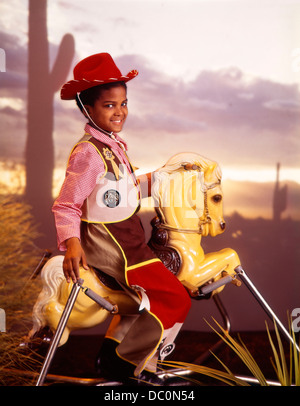 Des années 1970, peu d'AFRICAN AMERICAN BOY IN WAITING SUR TYPE PRINTEMPS BOUNCING HOBBY HORSE HAPPY SMILING Banque D'Images