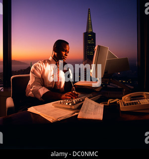 1980 AFRICAN AMERICAN MAN WORKING AT COMPUTER EXÉCUTIF APRÈS LES HEURES DE SAN FRANCISCO CA USA Banque D'Images