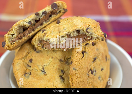 Un plat de crème aux noisettes cookies nougat rempli avec une cassée pour montrer la garniture sur un tissu coloré. Banque D'Images