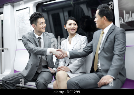 Les personnes d'affaires shaking hands in Subway train Banque D'Images