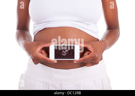 Jeune femme noire enceinte montrant une échographie photo de son ventre , isolé sur fond blanc - les peuples africains Banque D'Images