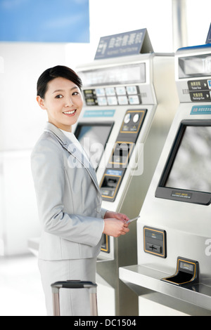 Young businesswoman using machine automatique de billets train station Banque D'Images