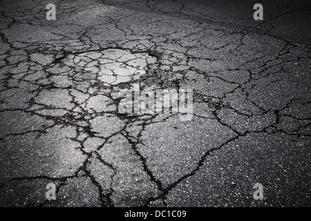 La route d'asphalte foncé avec des fissures. La texture d'arrière-plan Banque D'Images