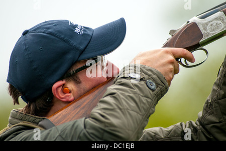 L'homme à tirer sur une simulation de tir jeu de tir d'argile portant une casquette de base Banque D'Images