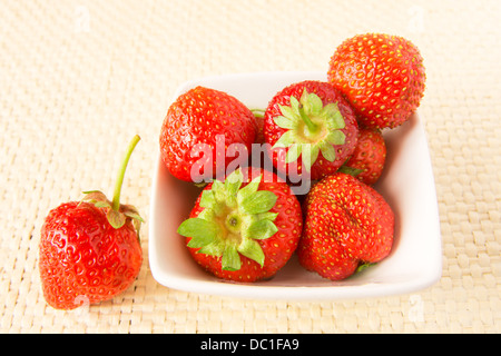 Pile des fraises avec des feuilles, entiers, Close up, sur fond blanc bambou (texture) avec copie espace horizontal, Banque D'Images