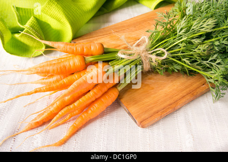 Carottes fraîches tas de feuilles sur planche de bois à la verticale Banque D'Images