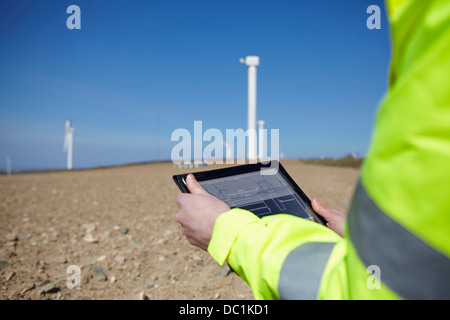 Gestionnaire de projet using digital tablet in front of wind farm Banque D'Images
