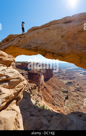 Walker debout sur Mesa Arch, Île dans le ciel, Canyonlands National Park, Utah, USA Banque D'Images