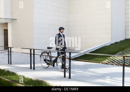 Mid adult businessman walking with bicycle Banque D'Images