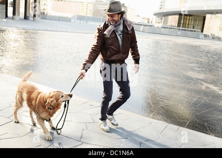 Mid adult man pulling laisse sur pet dog in city Banque D'Images