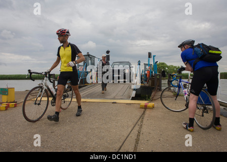 Les cyclistes du débarquement et l'embarquement la petite chaîne ferry traversant la rivière Yare dans Reedham sur les Norfolk Broads. Banque D'Images