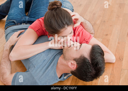 Jeune couple lying together sur plancher en bois Banque D'Images