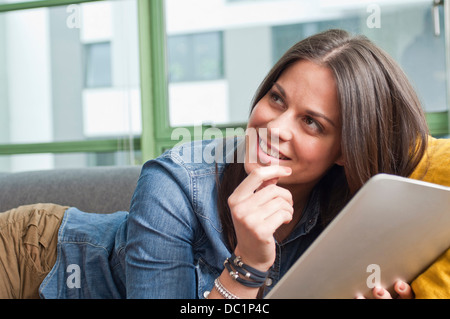 Close up of young woman lying on sofa holding digital tablet Banque D'Images