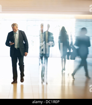 Businessman checking cell phone in lobby Banque D'Images