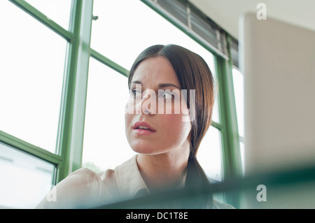 Young female office worker à la fenêtre de Banque D'Images