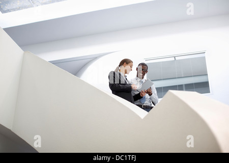 Businessman and businesswoman using digital tablet on escalier moderne Banque D'Images