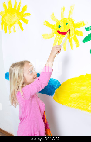 Jeune fille souriante peinture soleil sur mur Banque D'Images