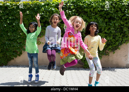 Quatre jeunes filles sautant dans jardin Banque D'Images