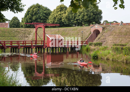 Les touristes en kayak kayak sur le canal autour de la forteresse dans le village de Bourtange Pays-bas passant un pont Banque D'Images