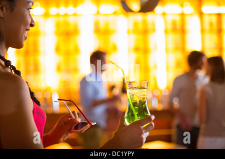 Jeune femme avec des lunettes de soleil et cocktail au club Banque D'Images