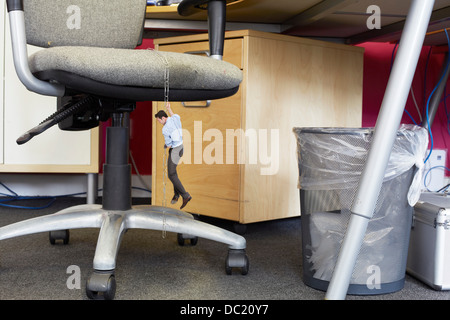 Businessman climbing down grand trombones sur chaise de bureau surdimensionné Banque D'Images