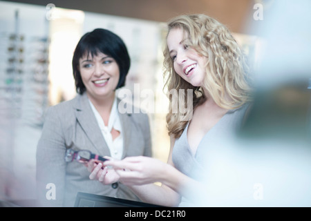 Jeune femme à la recherche de lunettes en boutique Banque D'Images