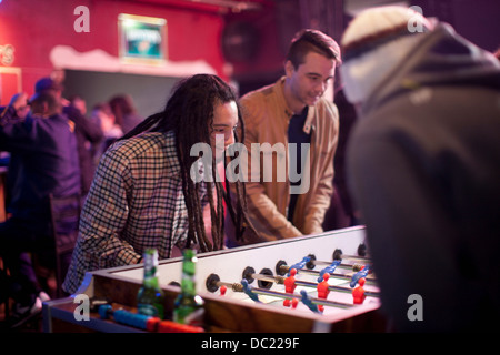 Groupe d'hommes jouer au baby-foot dans bar Banque D'Images