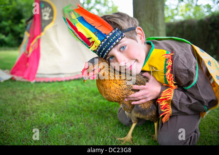 Garçon habillé en costume Amérindien holding chicken, portrait Banque D'Images